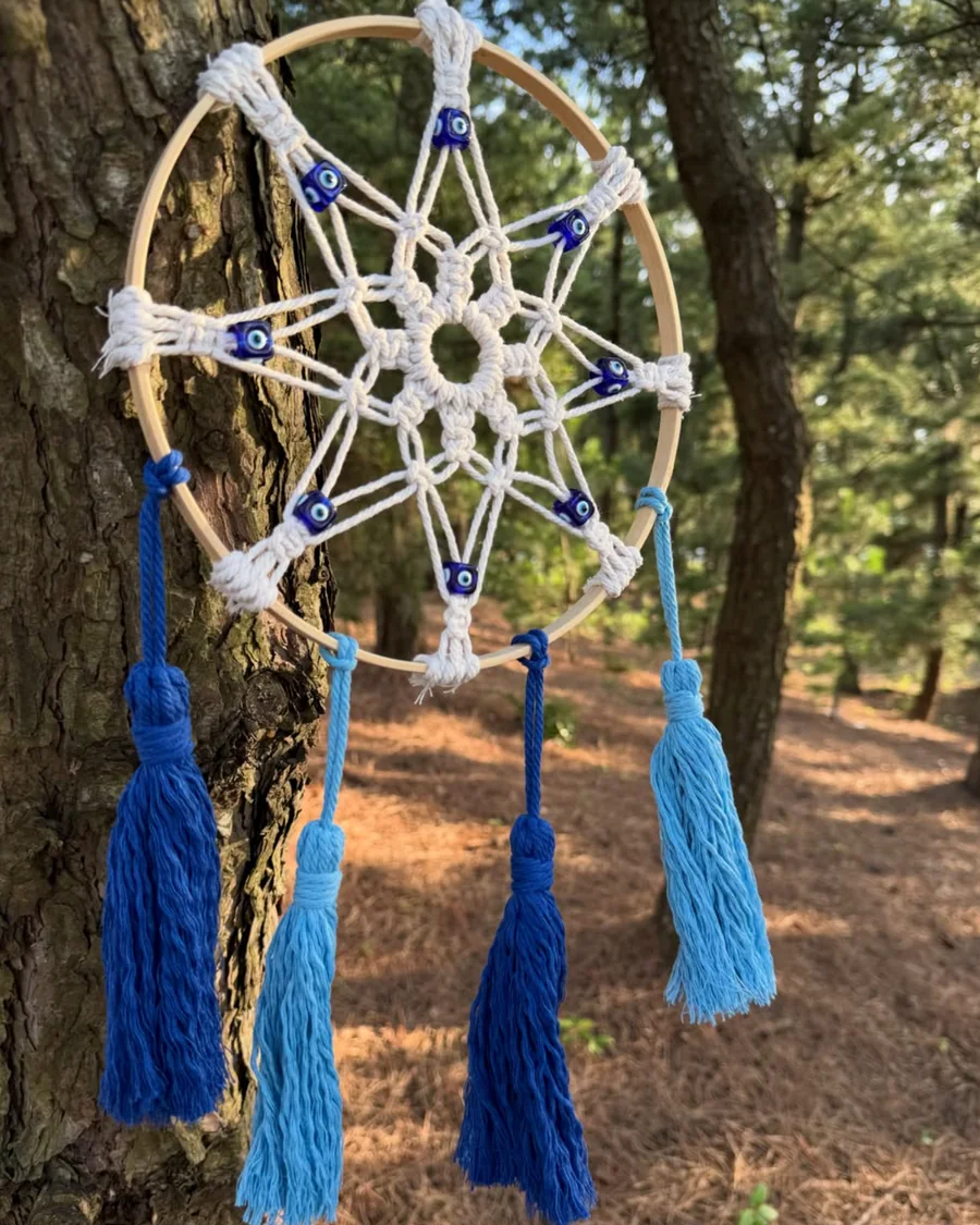 Filtro dos sonhos em macramê branco e azul em meio à natureza